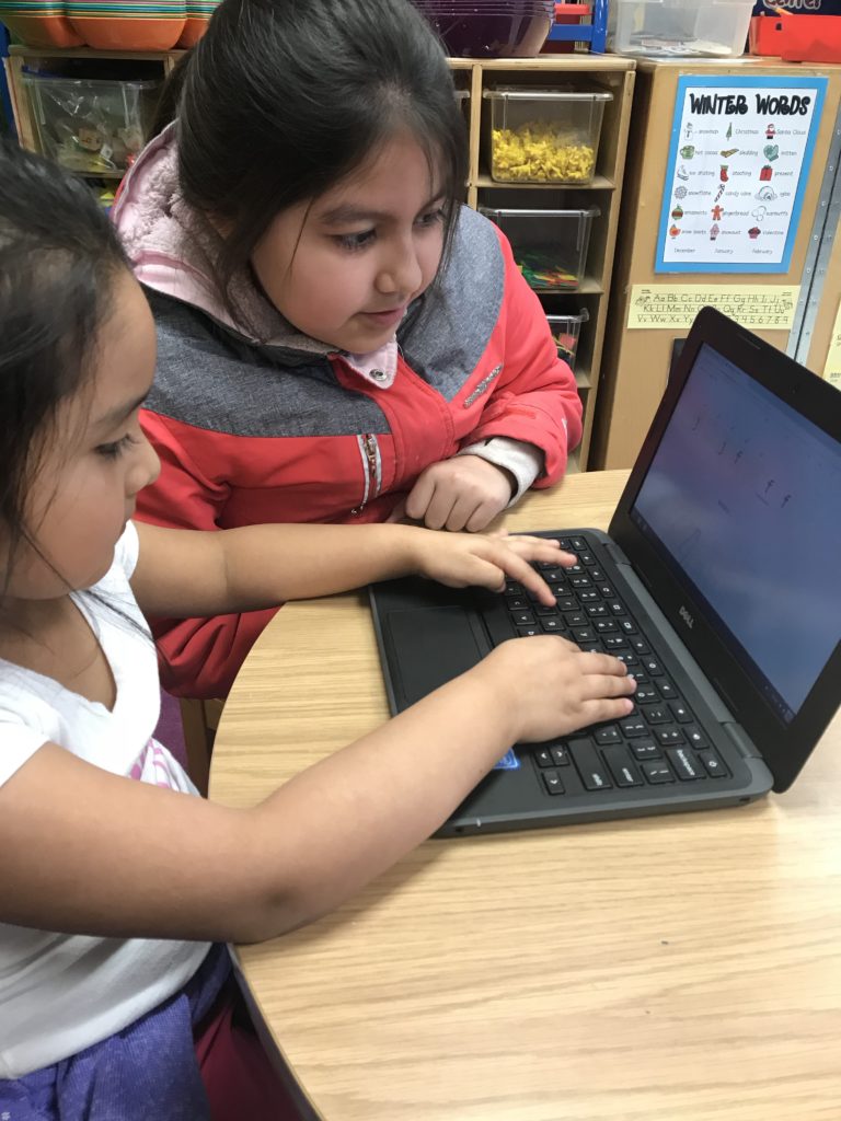 Two girls working on a computer together.