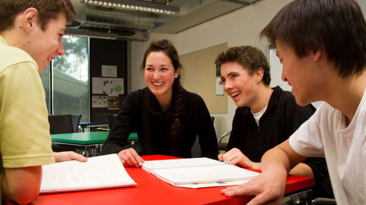 Four students smiling sitting around an orange table