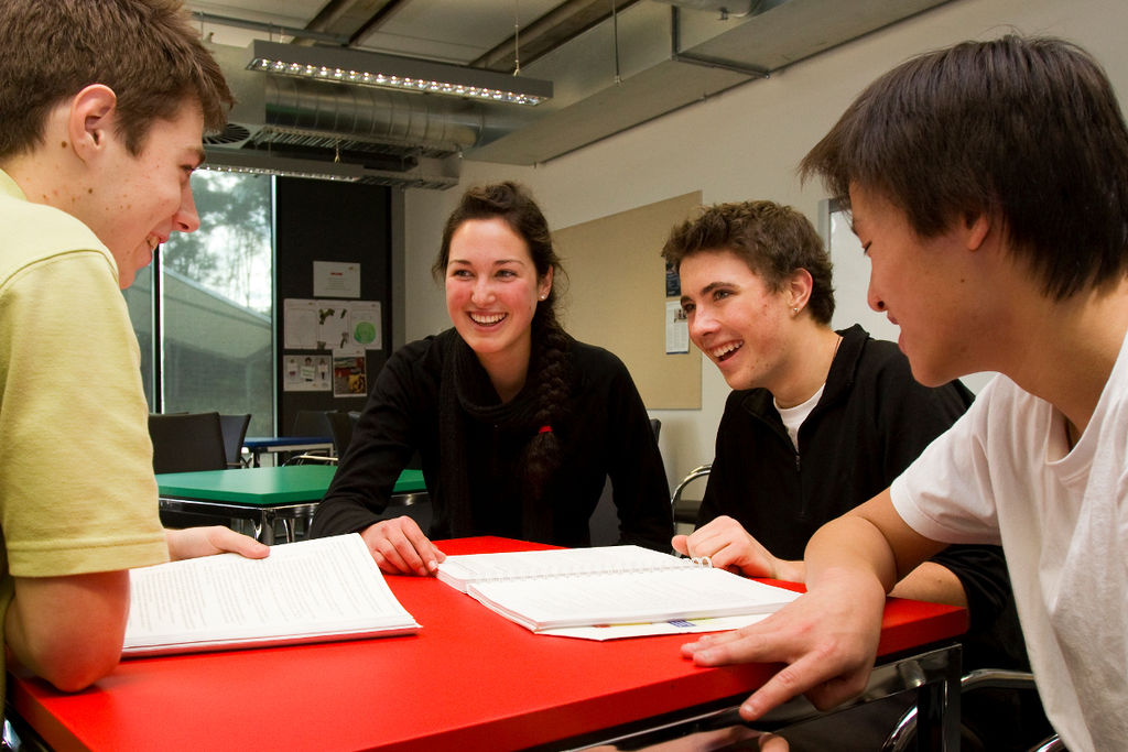 Four students smiling sitting around an orange table