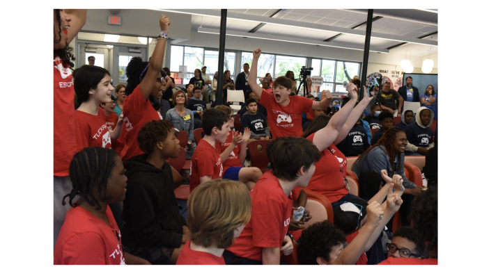 Middle school students in red shirts, cheering